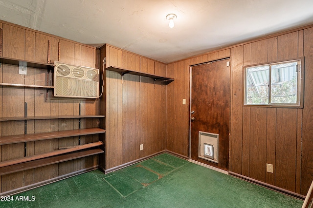 interior space featuring wooden walls, dark colored carpet, and a wall mounted air conditioner