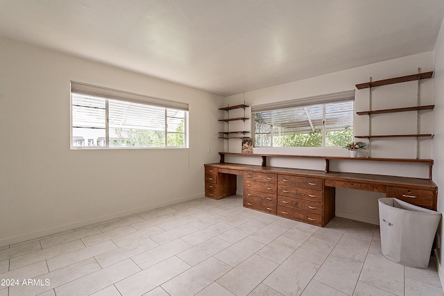 unfurnished office with built in desk and light tile patterned floors