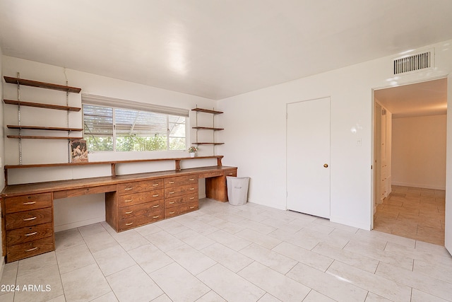 unfurnished office featuring built in desk and light tile patterned floors