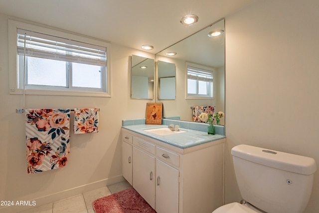 bathroom with toilet, vanity, tile patterned floors, and a healthy amount of sunlight