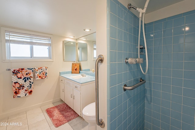 bathroom with tile patterned flooring, vanity, toilet, and a tile shower