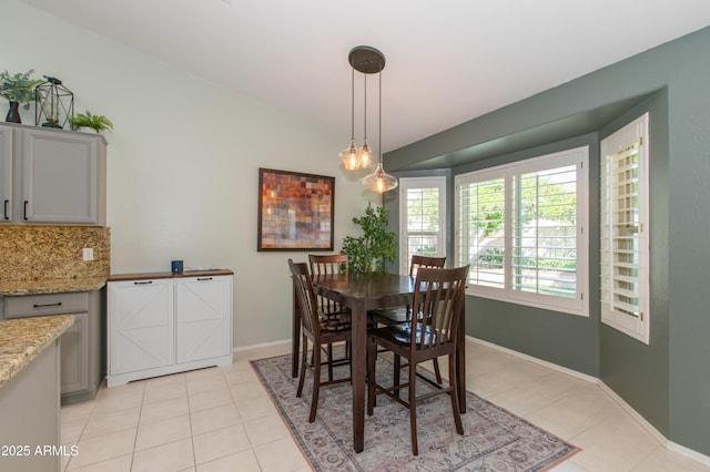 dining area with baseboards, light tile patterned floors, and lofted ceiling