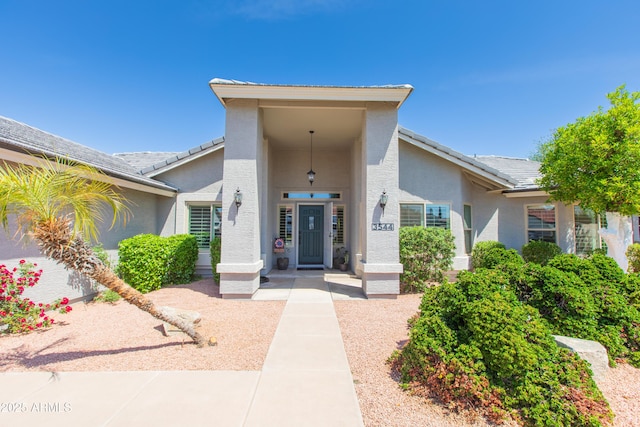 view of exterior entry with stucco siding and a tile roof