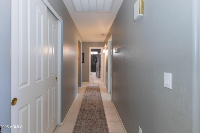 hall featuring baseboards, visible vents, and light tile patterned flooring