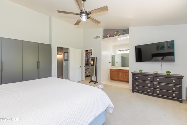 bedroom with visible vents, a closet, light carpet, high vaulted ceiling, and ensuite bath
