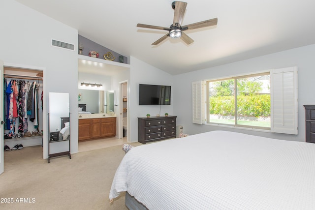 bedroom featuring light colored carpet, a closet, a walk in closet, visible vents, and lofted ceiling