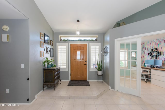 foyer with baseboards, vaulted ceiling, tile patterned floors, and plenty of natural light