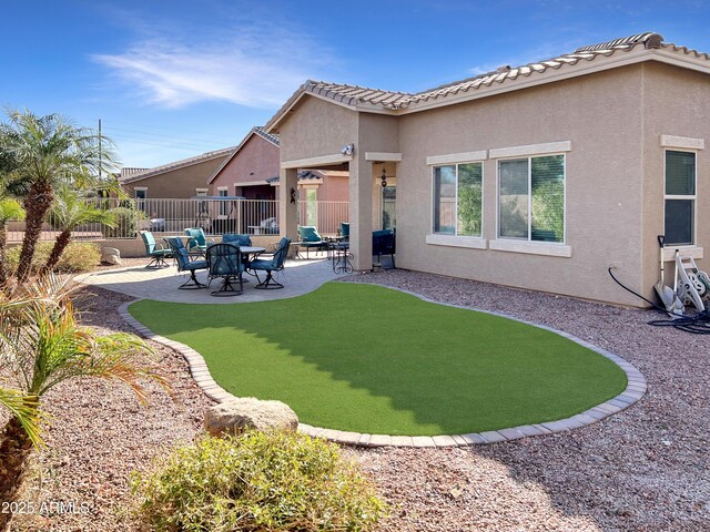 rear view of property with a tile roof, a patio area, fence, and stucco siding