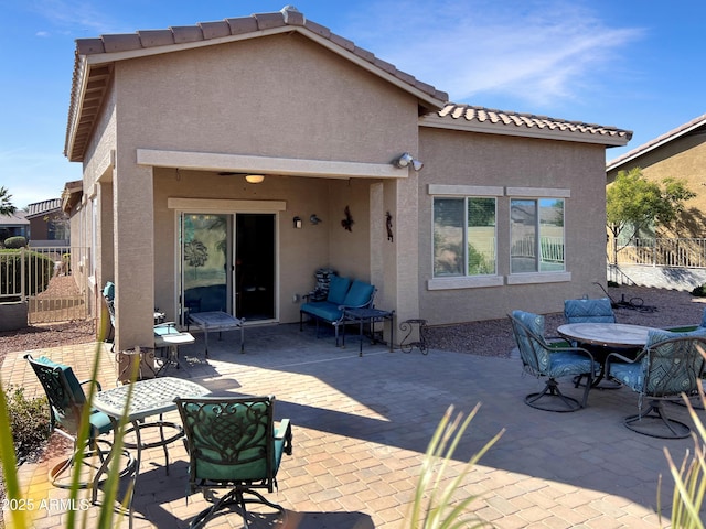 rear view of house featuring a patio area, fence, and stucco siding