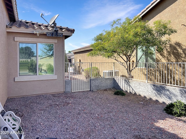view of side of property with a tile roof, fence, and stucco siding