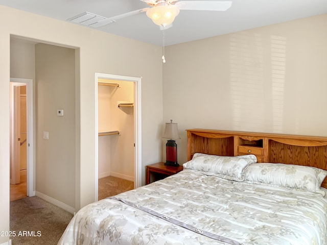 carpeted bedroom featuring ceiling fan, visible vents, baseboards, a closet, and a walk in closet
