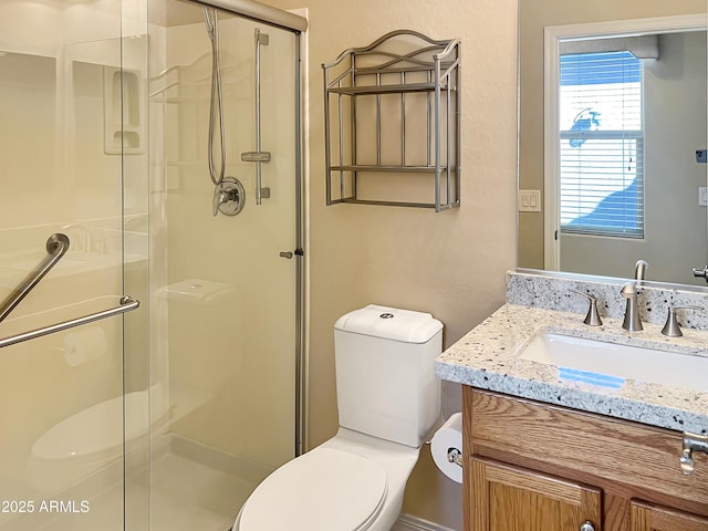bathroom featuring toilet, a stall shower, and vanity
