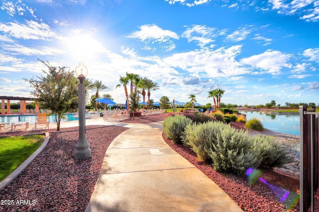 view of community featuring a water view, a swimming pool, and a patio
