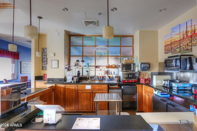 kitchen featuring brown cabinetry, black microwave, visible vents, and decorative light fixtures