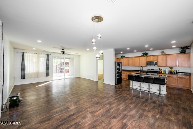 kitchen featuring appliances with stainless steel finishes, a kitchen breakfast bar, ceiling fan, sink, and an island with sink