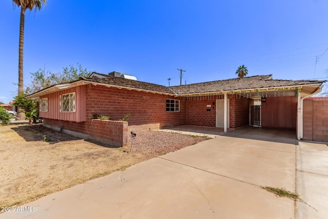 ranch-style home with a carport, brick siding, and driveway