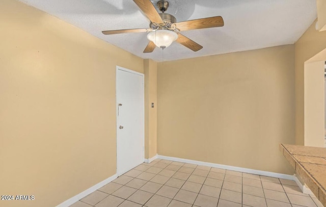 empty room with ceiling fan and light tile patterned floors