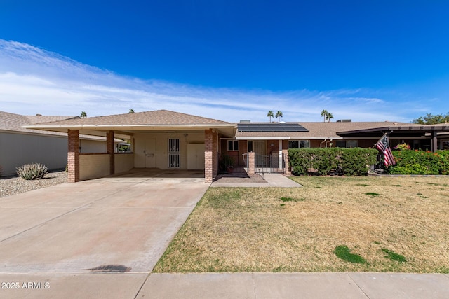 view of front facade featuring a carport, solar panels, driveway, and a lawn