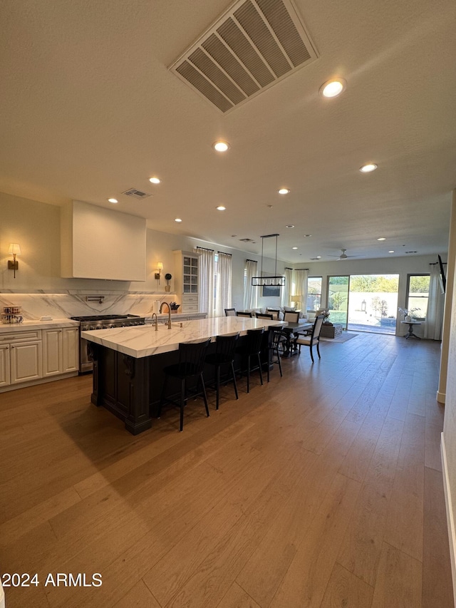 kitchen with white cabinets, a kitchen breakfast bar, a spacious island, and wood-type flooring