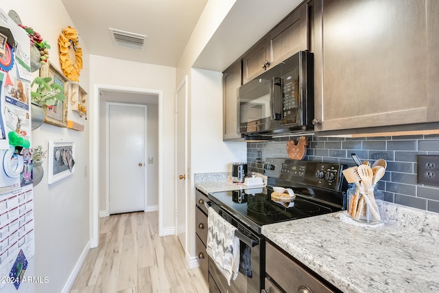 kitchen featuring light stone countertops, black appliances, dark brown cabinets, light hardwood / wood-style floors, and decorative backsplash