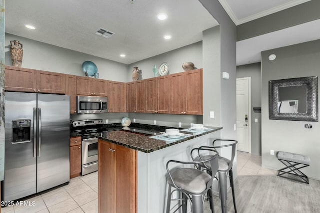 kitchen featuring light tile patterned floors, visible vents, appliances with stainless steel finishes, and dark stone counters