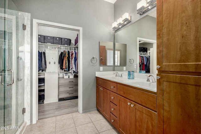 bathroom with a spacious closet, a sink, a shower stall, and tile patterned floors