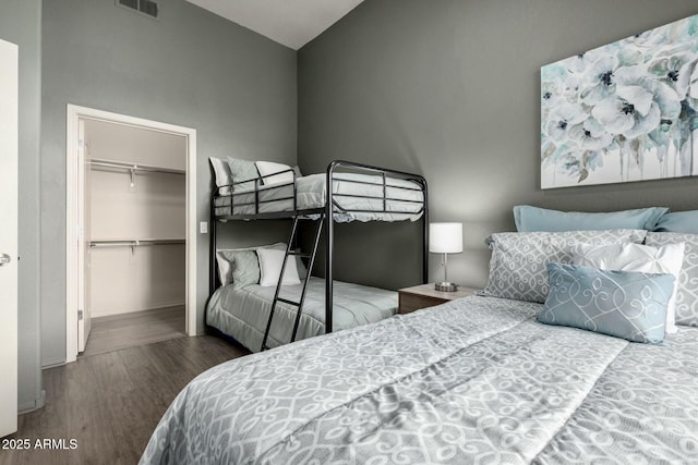 bedroom with a spacious closet, a closet, wood finished floors, and visible vents