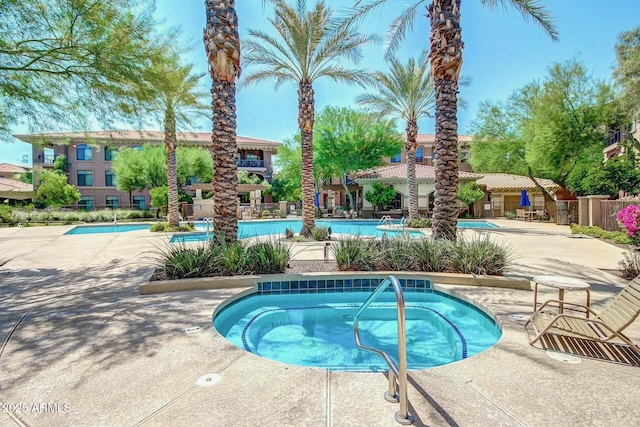 pool featuring a community hot tub, a patio, and fence