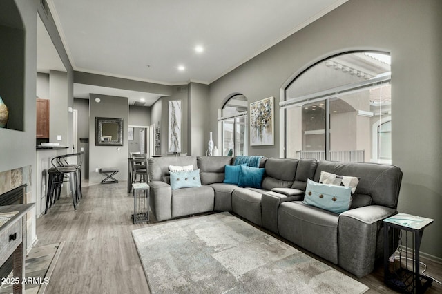 living area with crown molding, a fireplace, recessed lighting, wood finished floors, and baseboards