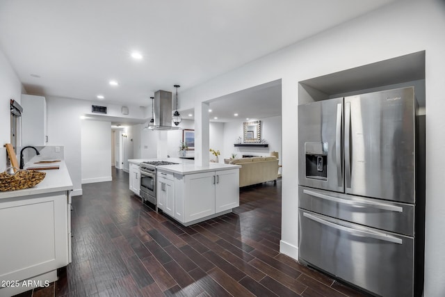 kitchen featuring appliances with stainless steel finishes, pendant lighting, white cabinets, dark hardwood / wood-style flooring, and island exhaust hood