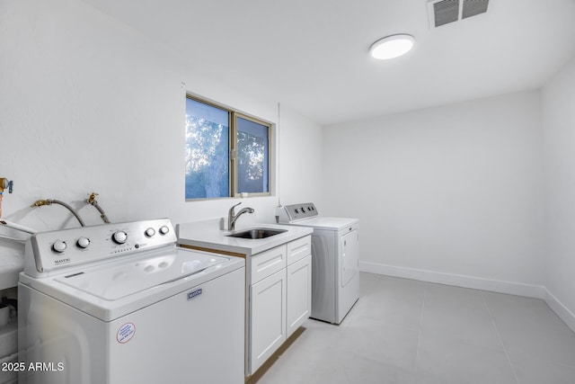 washroom with sink, light tile patterned floors, cabinets, and washing machine and clothes dryer