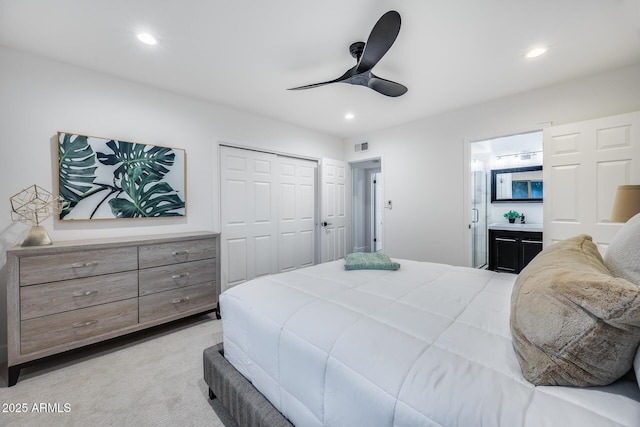 carpeted bedroom featuring ceiling fan, ensuite bath, and a closet