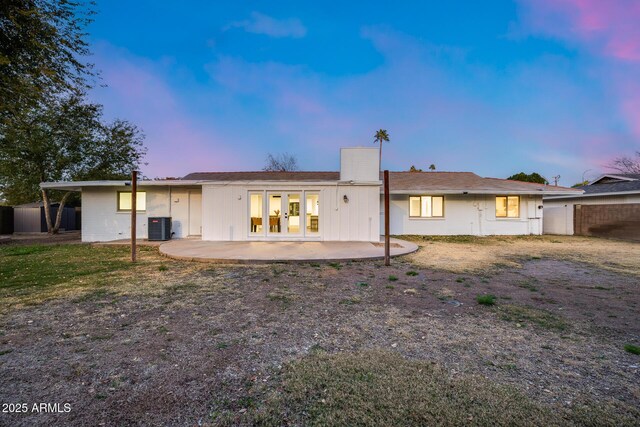 back house at dusk featuring central AC, french doors, and a patio area