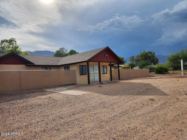 rear view of house featuring a mountain view and fence