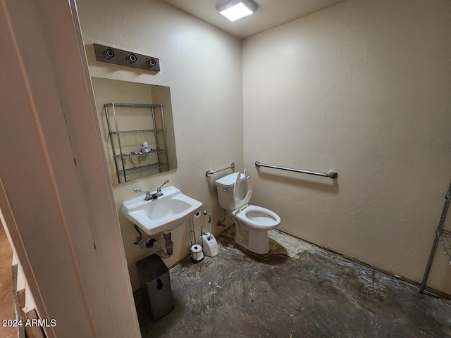 bathroom featuring a sink, a textured wall, toilet, and concrete flooring
