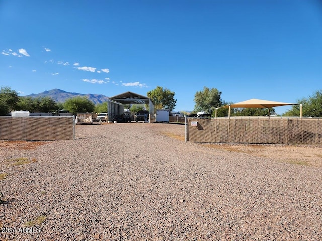 view of road with a mountain view, a gated entry, and gravel driveway