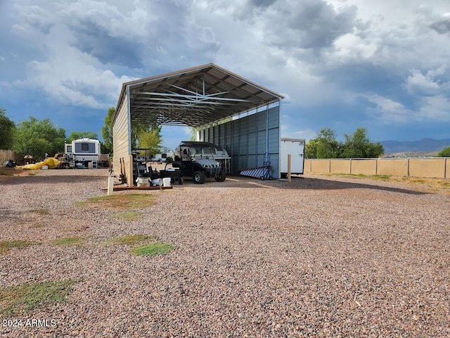 view of vehicle parking with a detached carport, fence, and dirt driveway