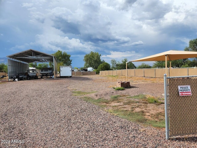 view of yard featuring a detached carport, fence, and driveway