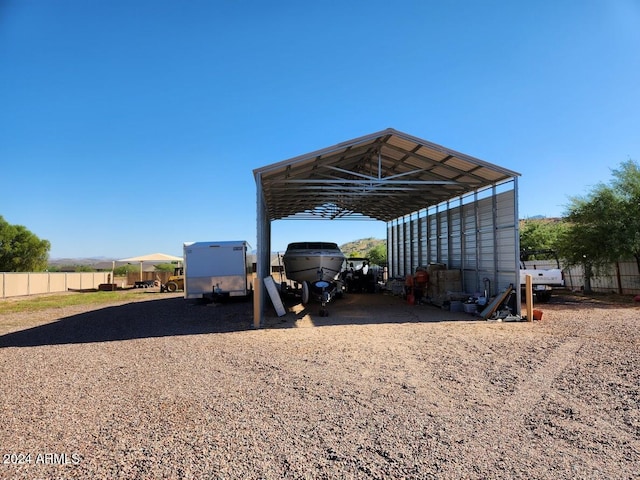 view of car parking with a detached carport, driveway, and fence