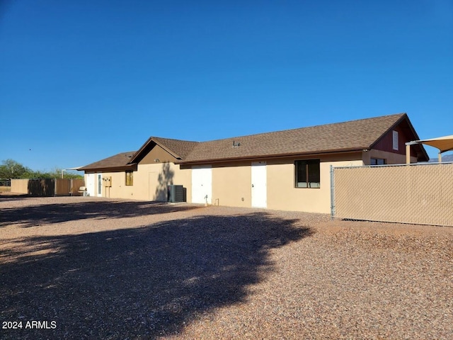 back of house with central AC, fence, and stucco siding