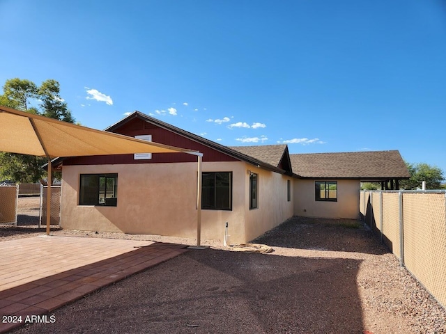 rear view of property featuring a patio, stucco siding, and fence