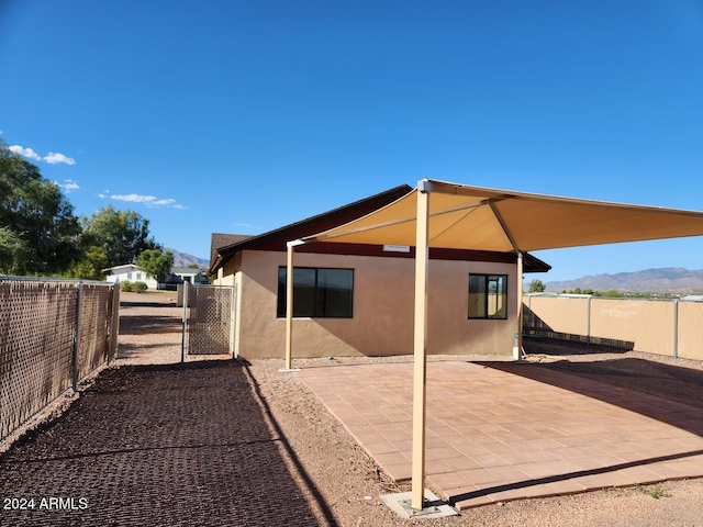 back of house with a patio area, a fenced backyard, a mountain view, and stucco siding