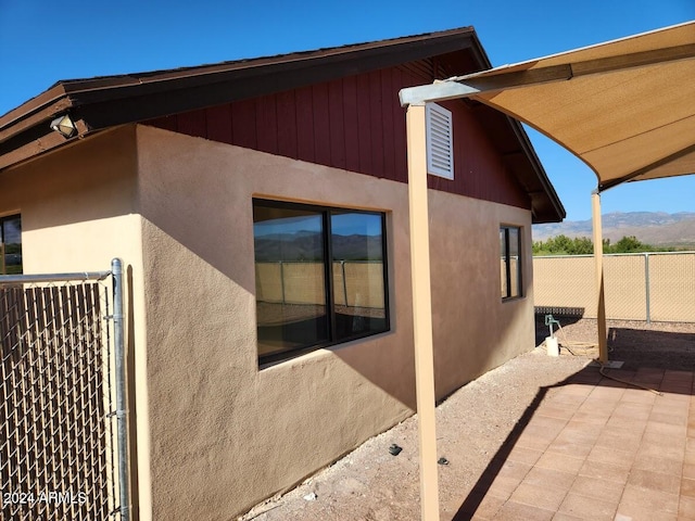view of home's exterior with a patio area, stucco siding, fence, and a mountain view