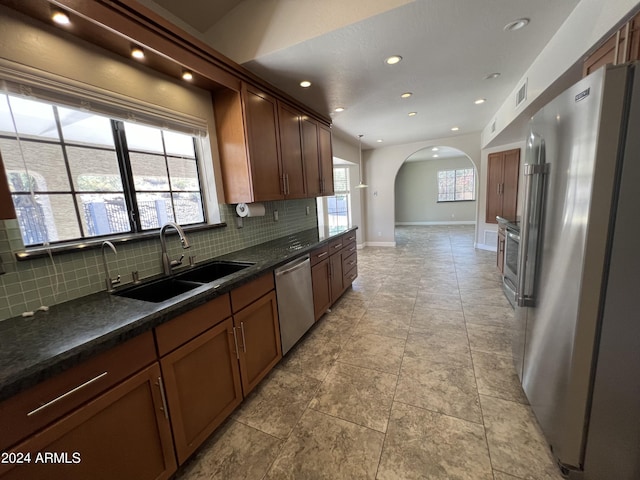 15230 N Blackbird Dr, Fountain Hills, AZ 85268 - kitchen with appliances with stainless steel finishes, a sink, arched walkways, dark countertops, and decorative backsplash