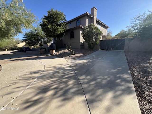 15230 N Blackbird Dr, Fountain Hills, AZ 85268 - view of home's exterior featuring a gate, stucco siding, and a chimney