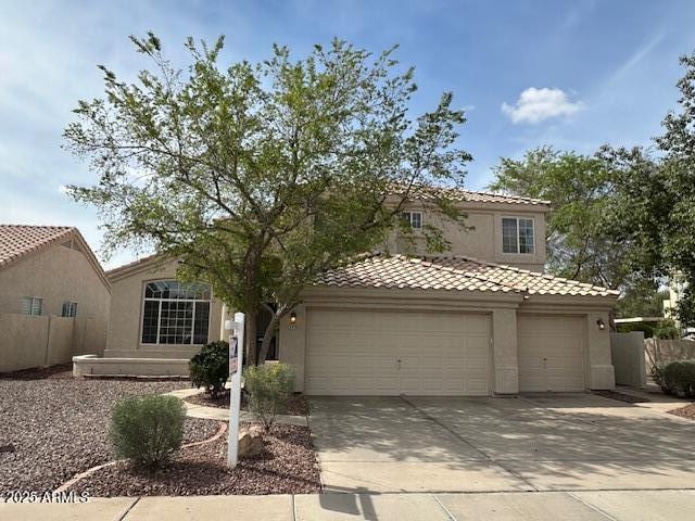 mediterranean / spanish house featuring stucco siding, driveway, an attached garage, and a tiled roof