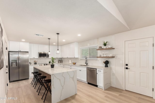 2348 E Diamond Ave, Mesa, AZ 85204 - kitchen featuring appliances with stainless steel finishes, a sink, a breakfast bar, white cabinets, and light wood-style flooring