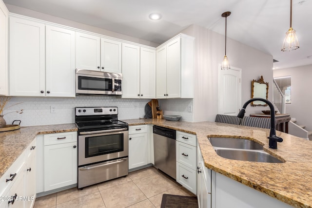 kitchen with stainless steel appliances, sink, pendant lighting, white cabinets, and light stone counters