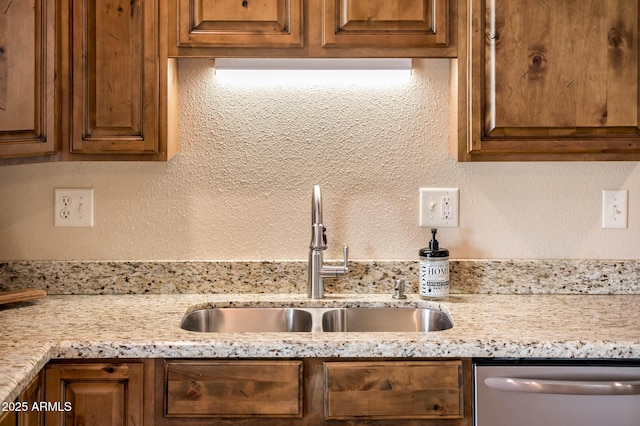 kitchen with light stone counters, stainless steel dishwasher, and sink