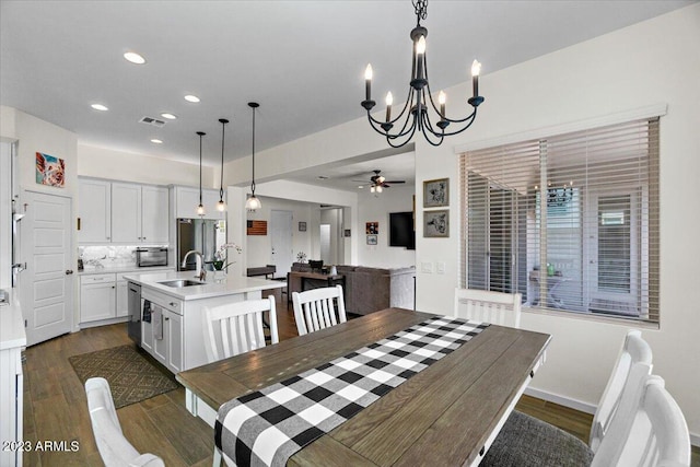 dining area featuring dark hardwood / wood-style flooring, ceiling fan with notable chandelier, and sink